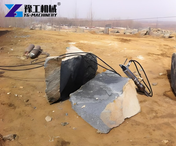 Hydraulic stone splitter splitting large rock block on site